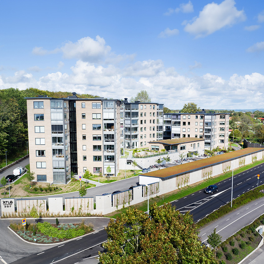 Drönarbild av ett modernt flerbostadshus med gröna omgivningar och en intilliggande väg i Varberg.
